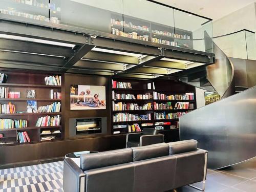 a library with a couch and shelves of books at Abbotsford Apartment: Yarra River & CBD nearby in Melbourne