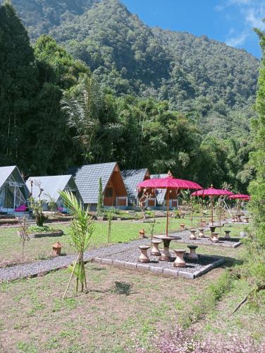 a group of tables and umbrellas in a field at Popitan Garden Campground & Glamping Bedugul in Bedugul