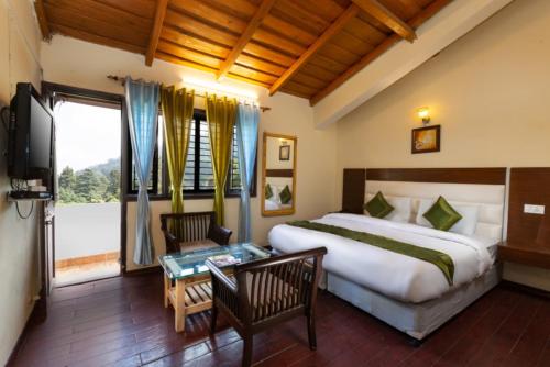 una camera d'albergo con un grande letto e una TV di Hotel Cottage Orchid Nainital - Parking Facilities - Luxury & Hygiene Room - Best Seller a Nainital