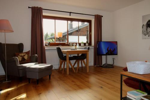 a living room with a table and a television at Isarkindl in Krün