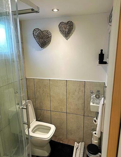 a bathroom with a toilet and two hearts on the wall at Sheepy village Leysdown in Leysdown-on-Sea
