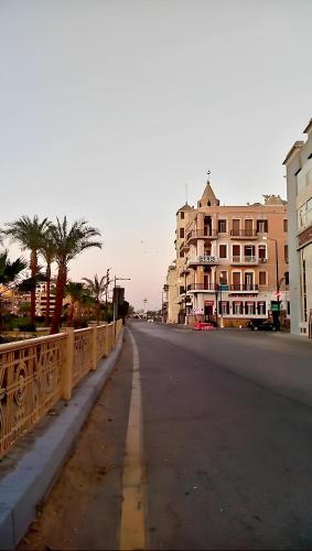 an empty street in a city with buildings and palm trees at Alam B&B Luxor in Luxor