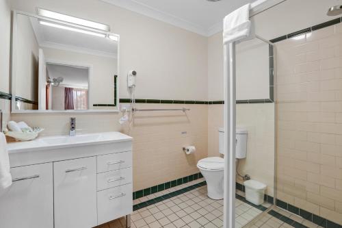 a bathroom with a sink and a toilet and a mirror at Terralong Terrace Apartments in Kiama