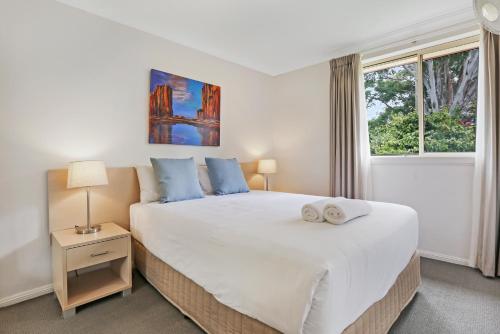 a bedroom with a large white bed and a window at Terralong Terrace Apartments in Kiama