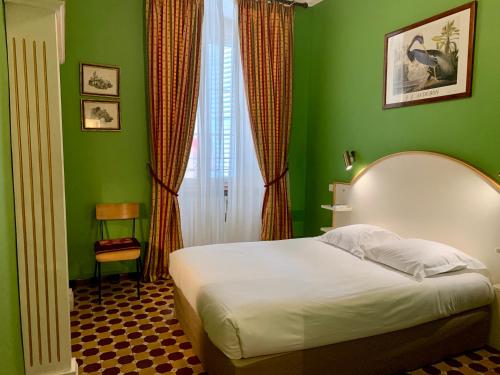 1 dormitorio con 1 cama con pared verde en Hotel Central Bastia en Bastia