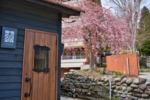 una casa blu con una porta in legno e un albero di root hakone a Hakone