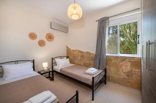 1 dormitorio con 2 camas y ventana en Gabriel apartment with a shared pool close to the beach, en Chorafakia