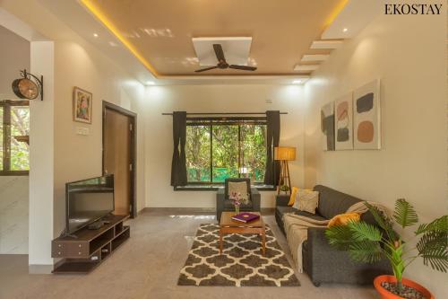 ein Wohnzimmer mit einem Sofa und einem TV in der Unterkunft EKOSTAY - Forestwood Villa in Alibag