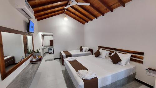 a bedroom with two beds and a ceiling fan at The Dream Inn Guesthouse Passikudah in Batticaloa