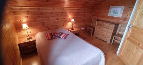 a bedroom with a white bed in a wooden room at CHALET MARAMU in Puy-Saint-Pierre