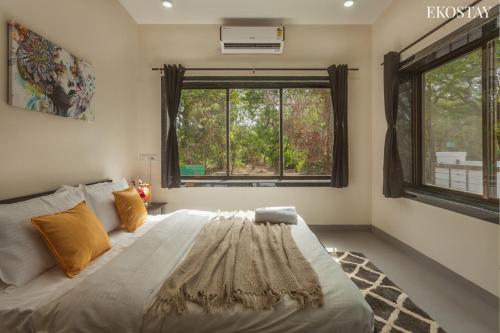 a bedroom with a large bed and a window at EKOSTAY - Forestwood Villa in Alibaug