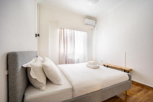 a bedroom with a bed with white sheets and a window at Acropolis Delux 1st FLR Aprt up 4 guests by LODGESPOT in Athens