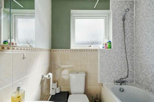 a bathroom with a white toilet and a bath tub at Hidden Safari home in Canterbury with free parking in Kent