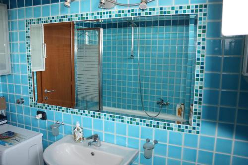 uma casa de banho em azulejos azuis com um lavatório e um chuveiro em Elegante appartamento trilocale em Milão