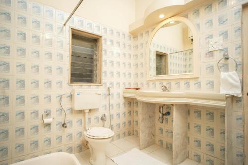 a bathroom with a toilet and a sink and a mirror at Nilambag Palace Hotel in Bhavnagar