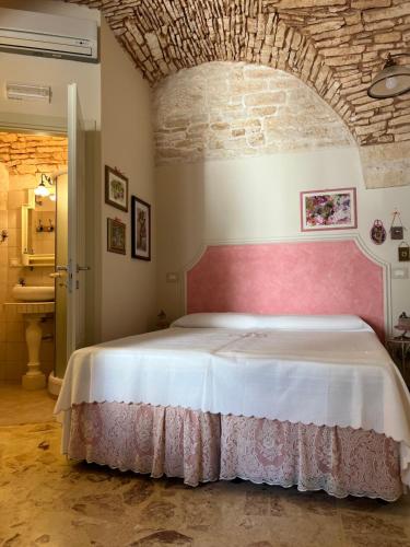 een slaapkamer met een groot bed met een roze hoofdeinde bij B&B A Casa di Marilù in Martina Franca