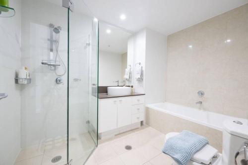 a bathroom with a shower and a tub and a sink at Cozy Retreat in Sydney CBD in Sydney