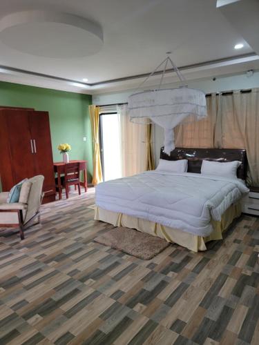 a bedroom with a large bed and a chair at Mew3 Apartment in Ndola