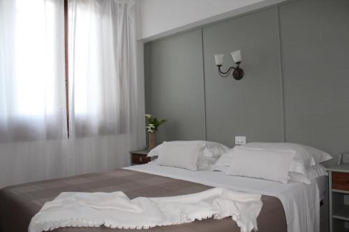 um quarto com uma cama grande e almofadas brancas em Ellea Resort em San Michele Salentino