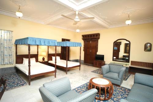 a bedroom with two beds and chairs and a mirror at Nilambag Palace Hotel in Bhavnagar