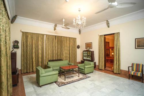a living room with green chairs and a table at Nilambag Palace Hotel in Bhavnagar