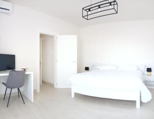 a white bedroom with a bed and a desk and a chair at mya luxury rooms and wellness in Melendugno