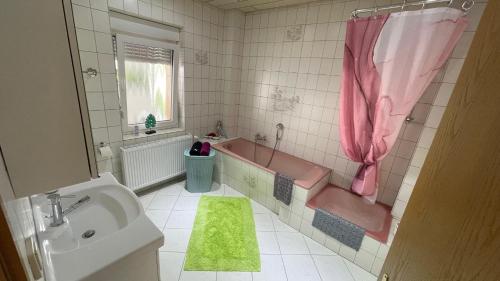y baño con bañera de color rosa, lavabo y bañera. en Ferienwohnung -Isola Madre en Biebesheim