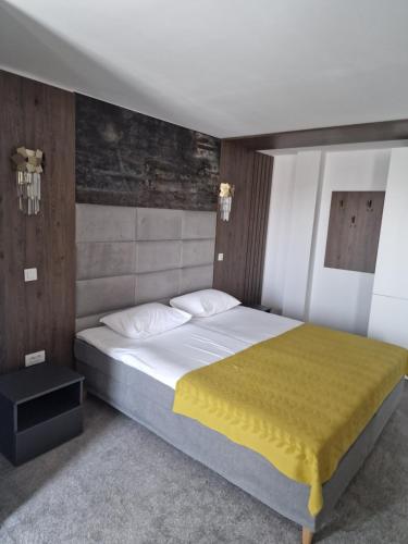 een slaapkamer met een groot bed en een gele deken bij Hotel City Break in Galaţi