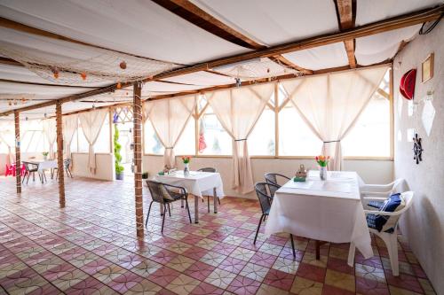 a restaurant with white tables and chairs and windows at Casa Irina 2Mai in 2 Mai