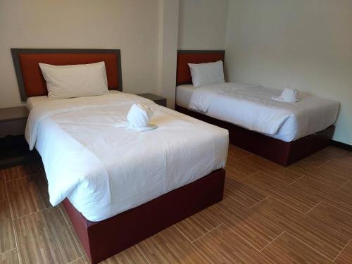 two beds with white sheets and a white towel on them at Sisina Resort in Ban Krut