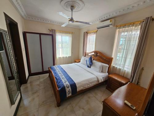 a bedroom with a bed and a table and windows at Ibranad Apartments in Accra