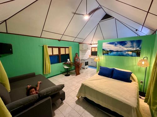 a child is laying on a couch in a bedroom at « Le Green House » by Meri lodge Huahine in Fare