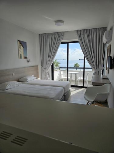 a hotel room with two beds and a balcony at Les Palmiers Sunorama Beach Apartments in Larnaka