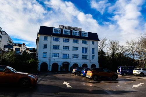 a large white building with cars parked in a parking lot at The Trouville Bournemouth in Bournemouth