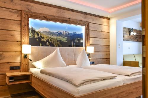 a bedroom with a bed with a large window at Hotel Lärchenhof in Lermoos