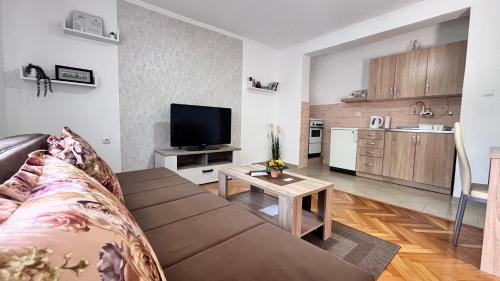 a living room with a couch and a tv and a kitchen at Apartman MIM in Trebinje