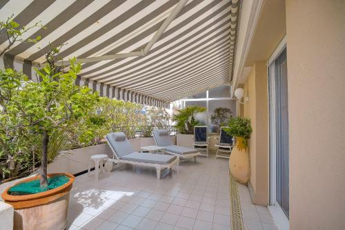 an outdoor patio with chairs and tables and awning at Le Cap St-Charles - Spacieux dernier étage - terrasses - climatisation - parking in Juan-les-Pins