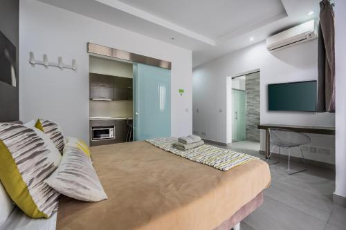 a bedroom with a large bed and a television at Jules Suites in St. Julianʼs