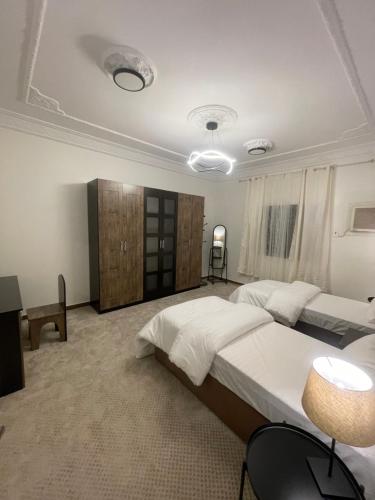 1 dormitorio grande con 2 camas, mesa y sillas en شقة كدي 1, en Al Masfalah