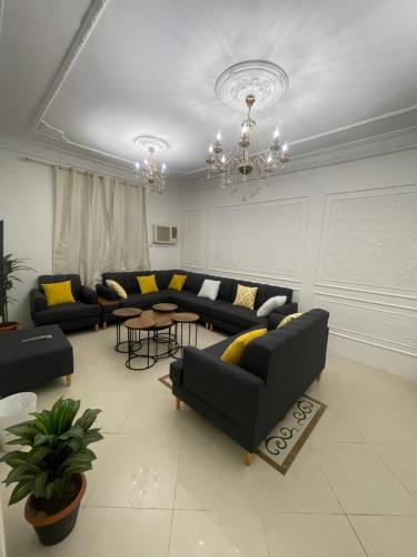 una sala de estar con sofás y una lámpara de araña. en شقة كدي 1, en Al Masfalah