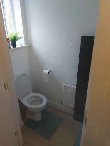 a white bathroom with a toilet and a window at Private Room in Manchester