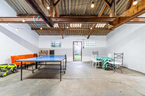 Cette chambre comprend une table de ping-pong et des chaises. dans l'établissement Grande et belle maison lumineuse avec jardin à 20 mn de Paris, à Gennevilliers