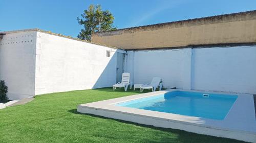 a small swimming pool in a yard with two chairs at Casa de campo con piscina in Chiclana de la Frontera