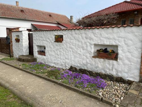 un edificio blanco con flores en un patio en Sétány Apartman-és Vendégház en Tiszafüred