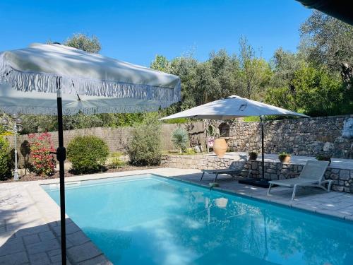 a swimming pool with two chairs and an umbrella at Mas Lou Piastoun in Fayence