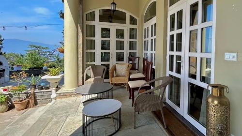 a patio with tables and chairs on a porch at The Magnolia Lodge in Almora