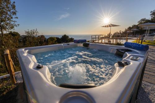 a jacuzzi tub with the ocean in the background at Dimora Maiuri L'Olivella in Anacapri