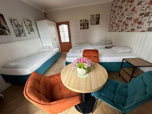 a room with two beds and a table with flowers on it at Forteca, pokoje gościnne nad stawem in Dzierżoniów