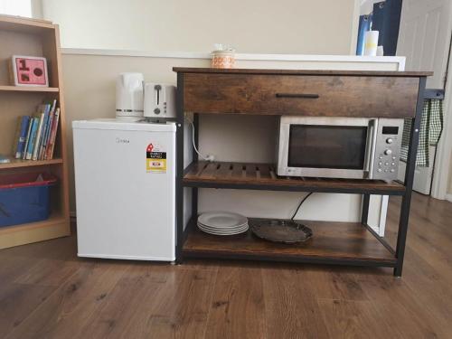 a microwave on a shelf next to a refrigerator at Cozy Half Moon Bay Homestay in Auckland