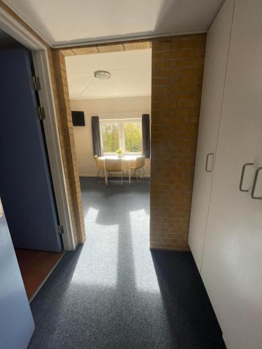 a hallway with a room with a table and a window at Idrætscenter Jammerbugt in Fjerritslev